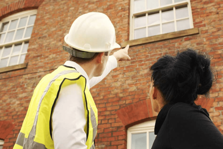 Engineer and colleague examining exterior wall